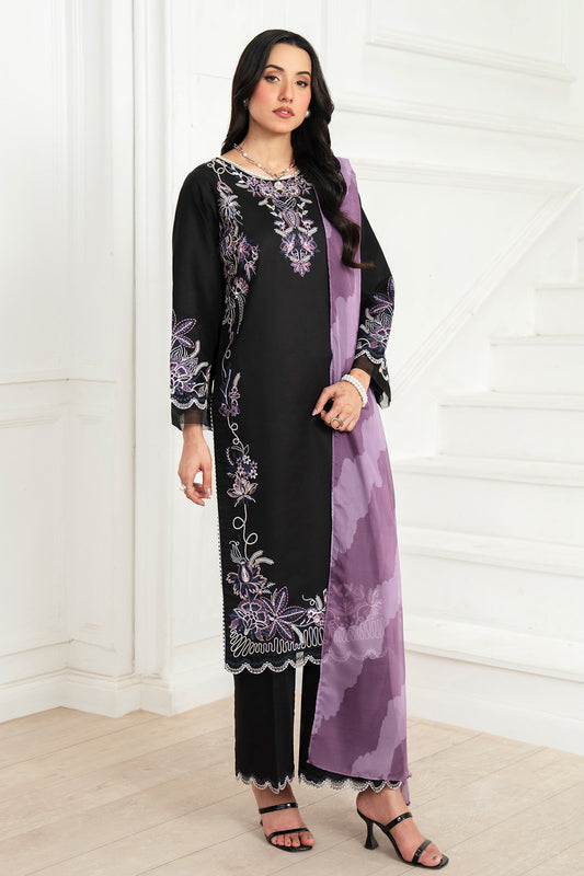 Woman wearing a black and purple embroidered outfit with a matching scarf indoors.