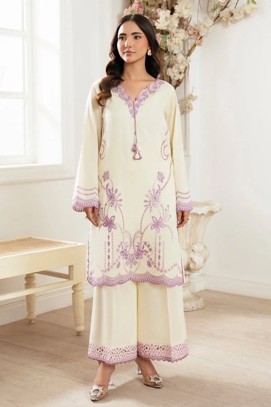 Woman wearing a cream and purple embroidered outfit in a bright room.
