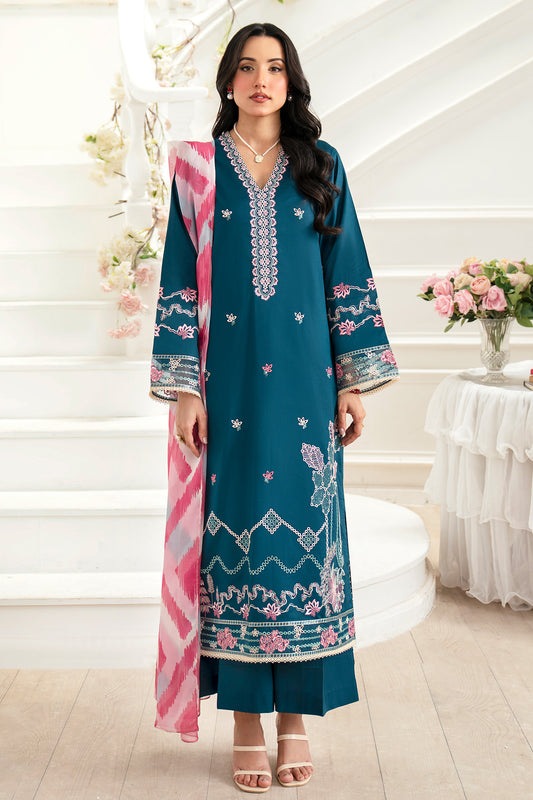 Woman wearing a teal and pink embroidered outfit in a decorated room.
