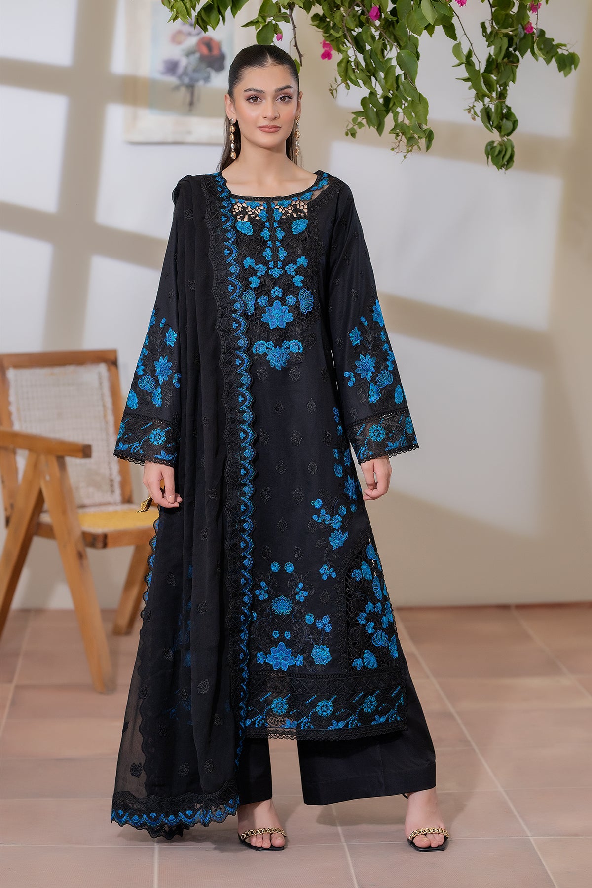 Woman wearing a black dress with blue floral patterns in an indoor setting.