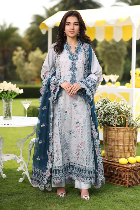 A woman wearing a traditional-style dress with floral embroidery, consisting of a shirt, dupatta, and trousers, in shades of teal and liver.
